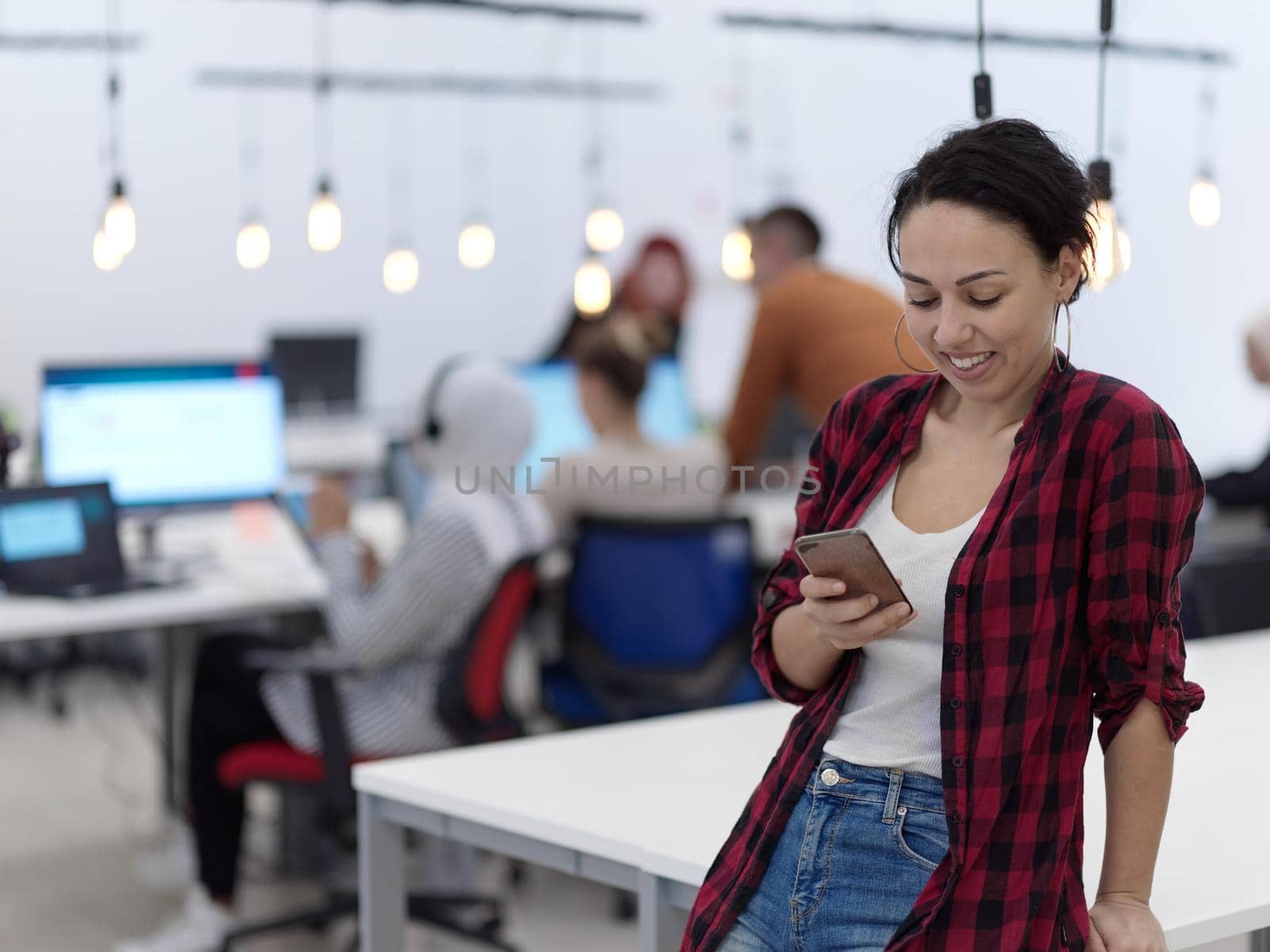 business woman portrait  in open space startup coworking office as influencer  using smart phone, tablet computer