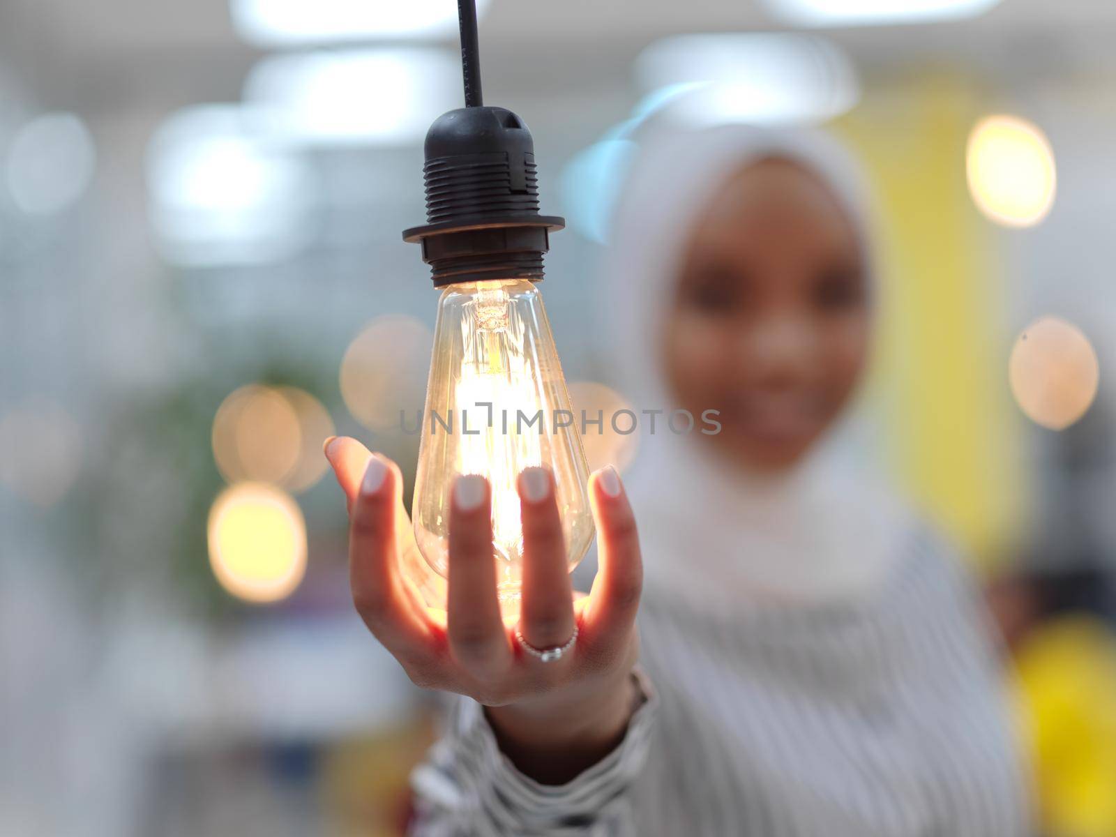 african muslim businesswoman holding hands around light bulb concept of smart saving energy and busines creative solutions
