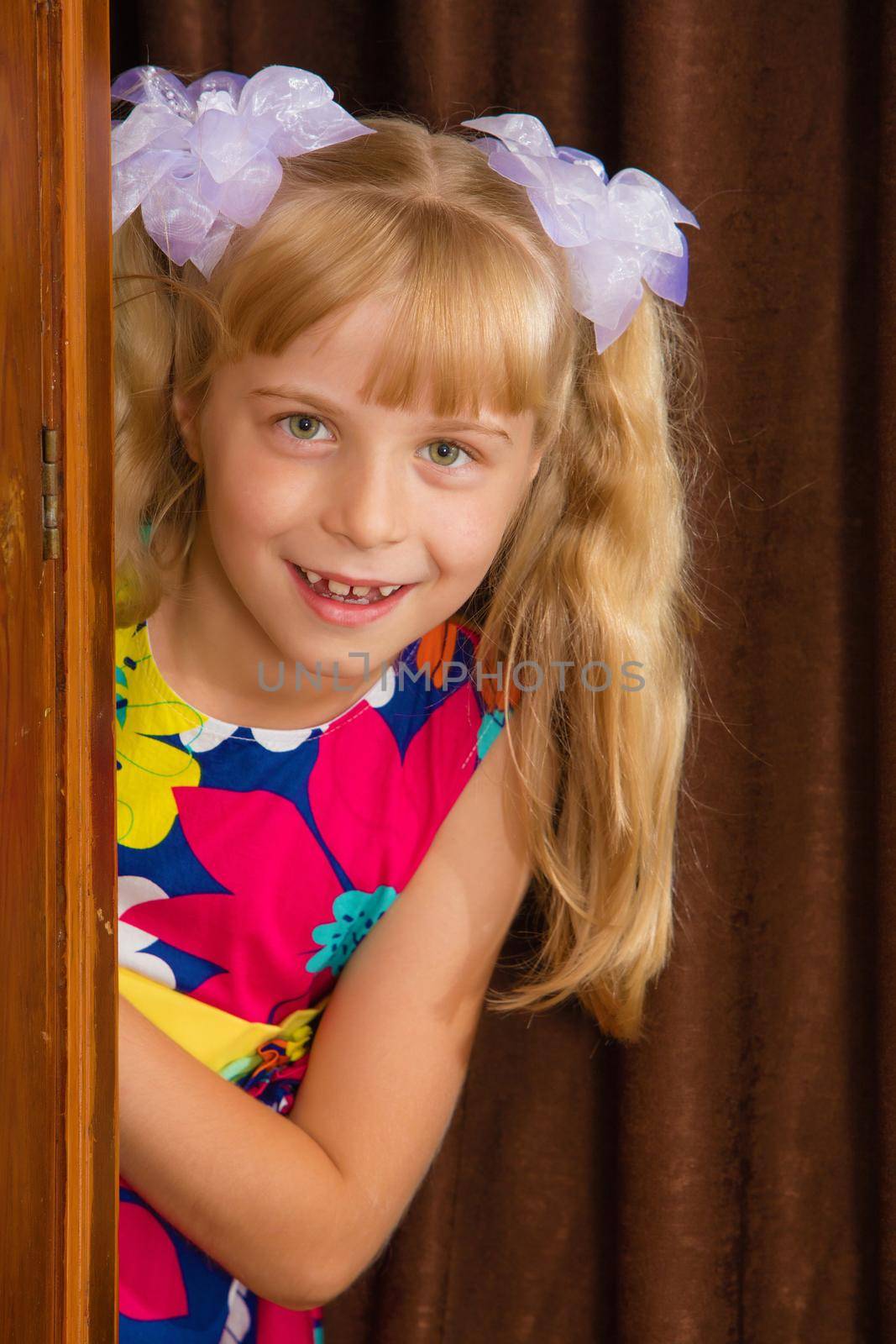 Laughing little girl hid behind an old wardrobe . retro style