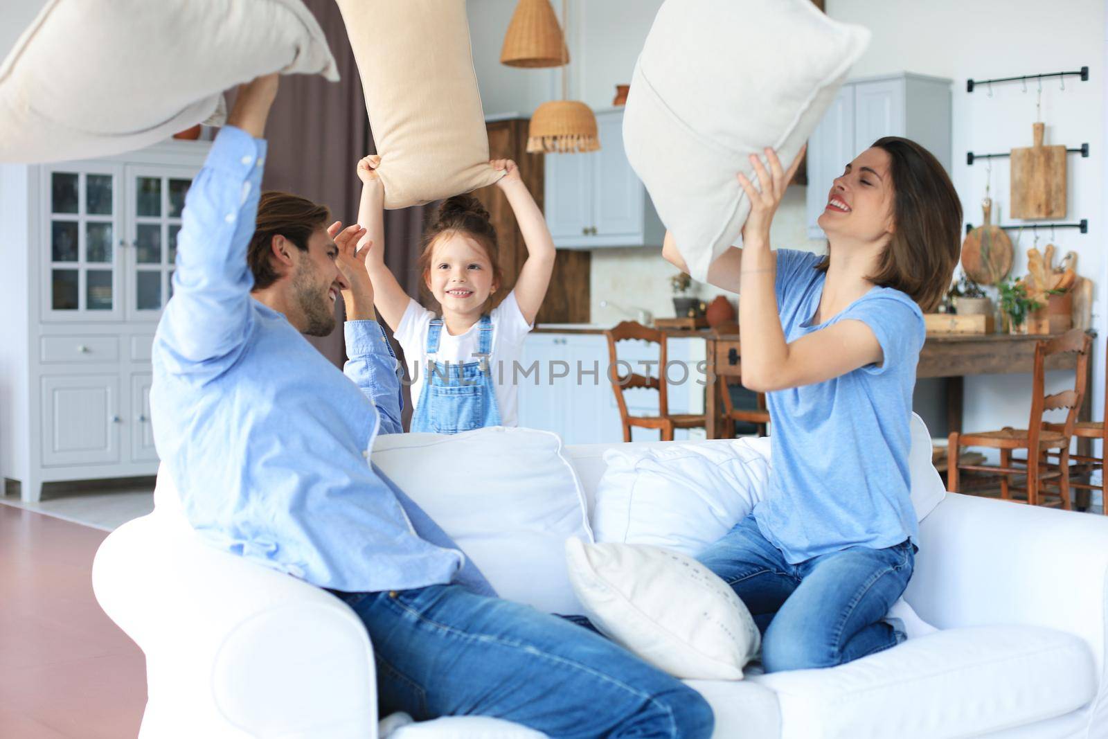Happy young family having fun with pillows on sofa. by tsyhun