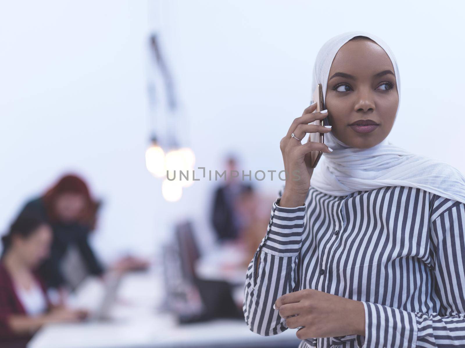 african muslim businesswoman using smart phone  wearing hijab at creative modern startup coworking open space office