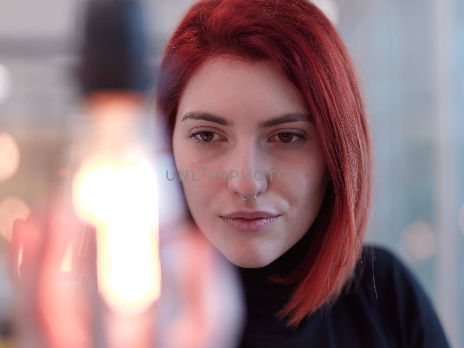 redhead businesswoman at office holding a hand around light bulb representing concept of business solutions idea and green energy