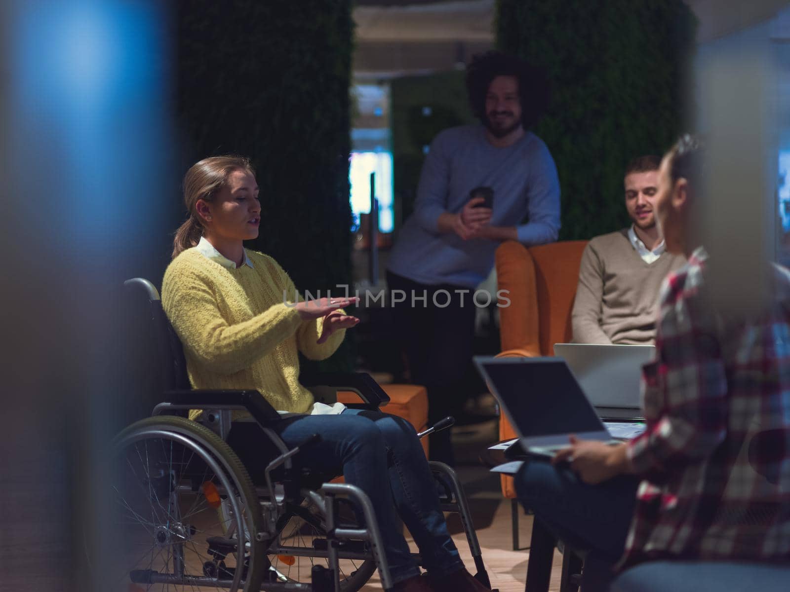 Disabled businesswoman in a wheelchair having a meeting with the diverse business people team at modern startup open space office 