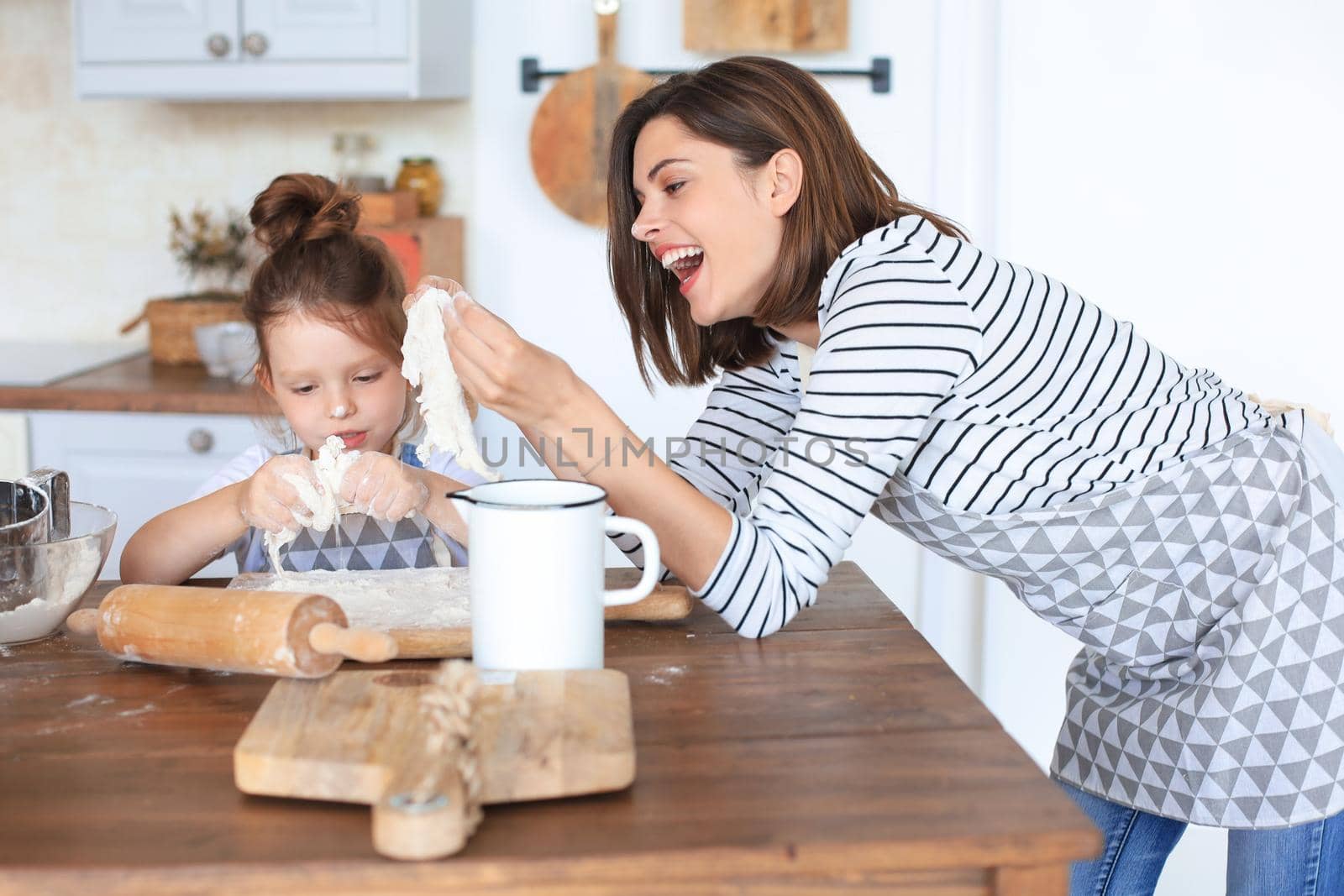 Playful little girl cooking at kitchen with her loving mother