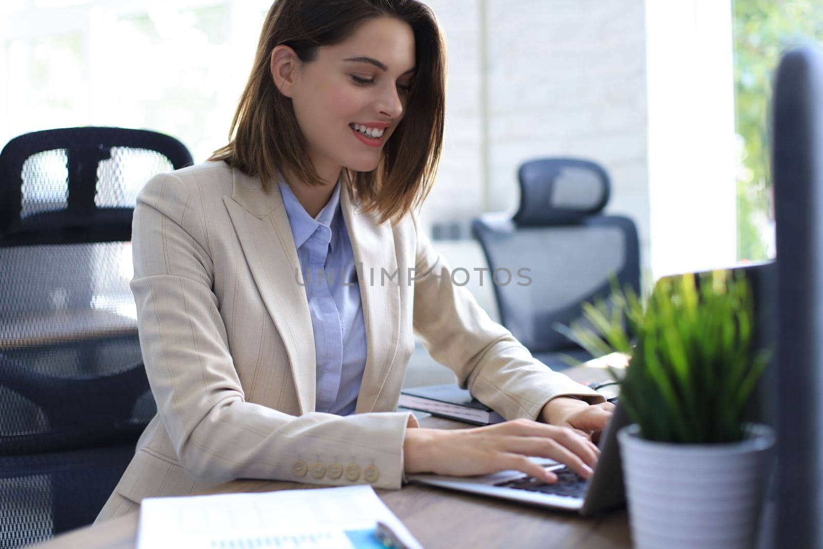 Smiling pretty woman sitting at table, looking at laptop screen. Happy entrepreneur reading message email with good news, chatting with clients online. by tsyhun