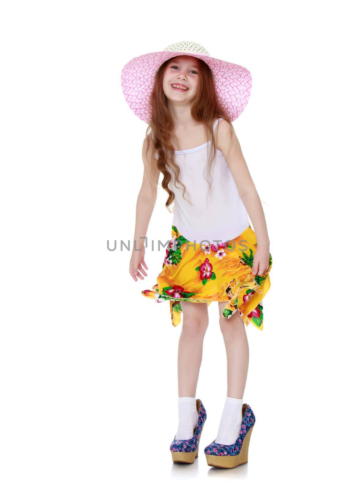 Nice little girl in a pink hat and a white tank top without a pattern . The girl wore on his feet shoes with high heels - Isolated on white background