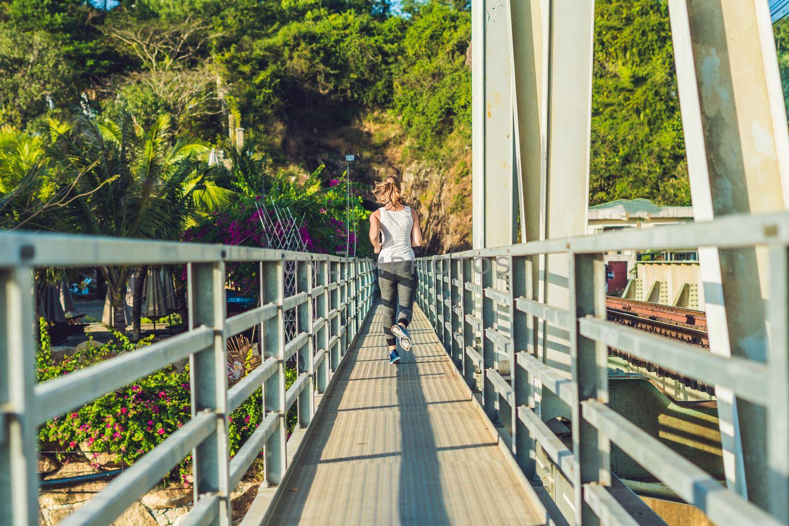 Beautiful woman running over bridge during sunset.