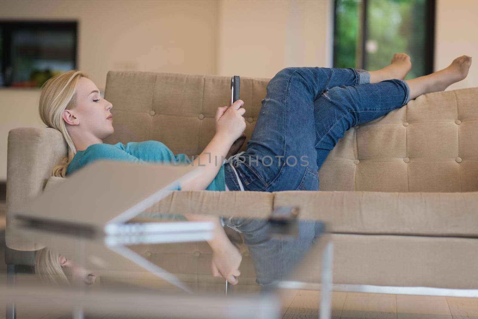 young happy woman on sofa using tablet computer at luxury home