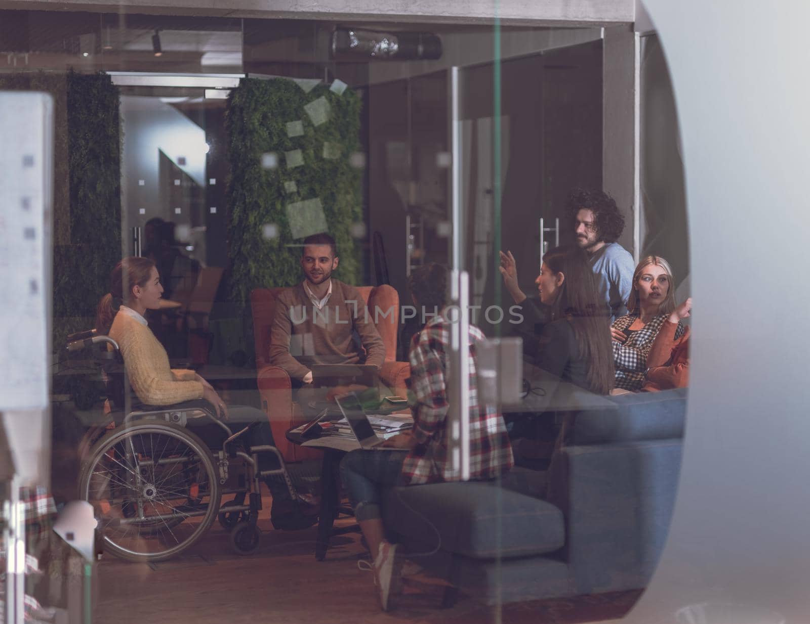 Disabled businesswoman in a wheelchair having a meeting with the diverse business people team at modern startup open space office 