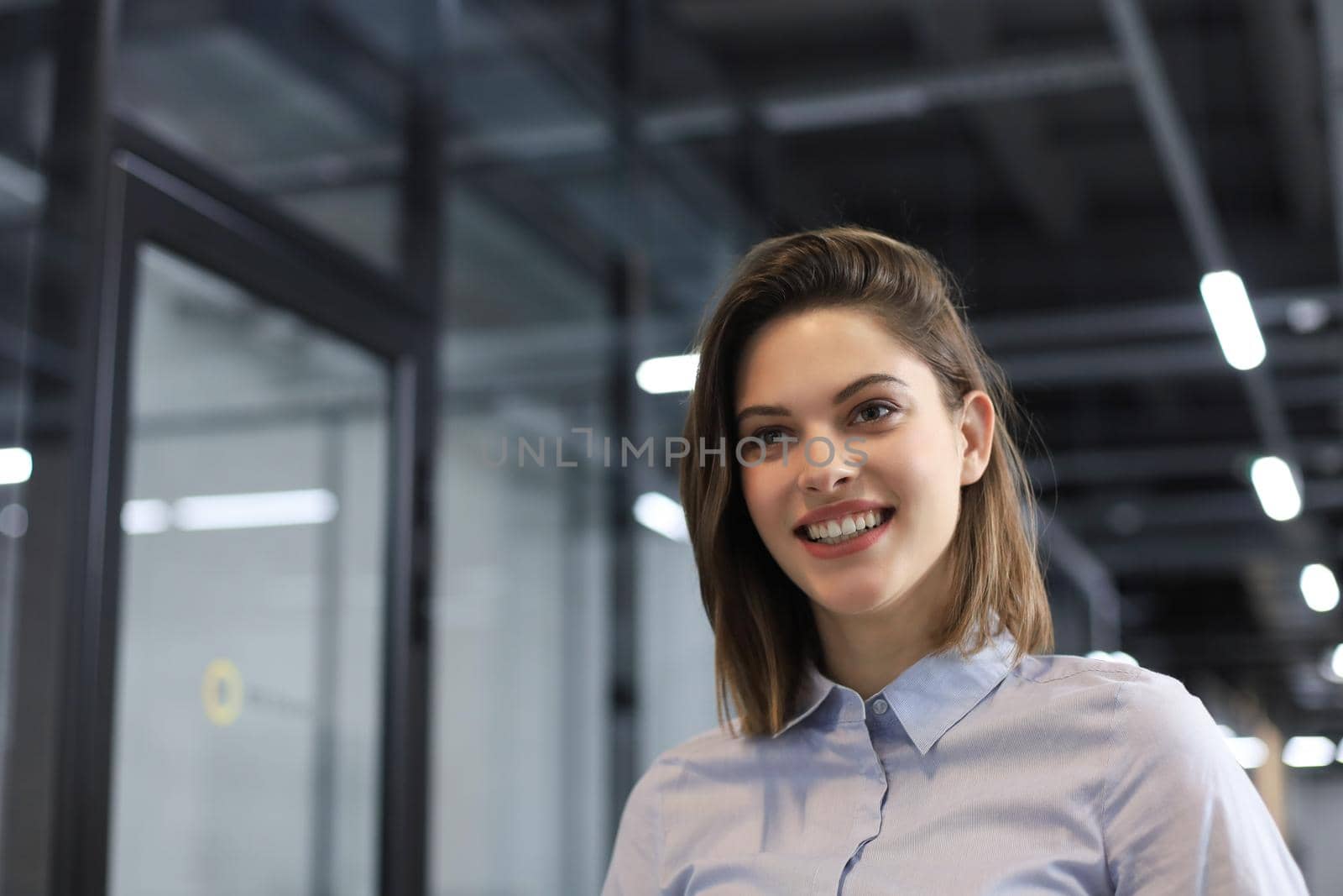 Attractive business woman smiling while standing in the office. by tsyhun