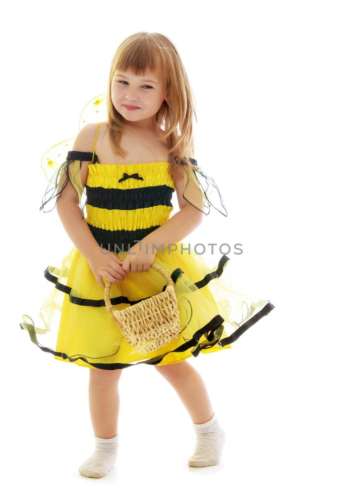 Beautiful little blonde girl in a black and yellow striped bee costume, holding a wicker basket.Isolated on white background.