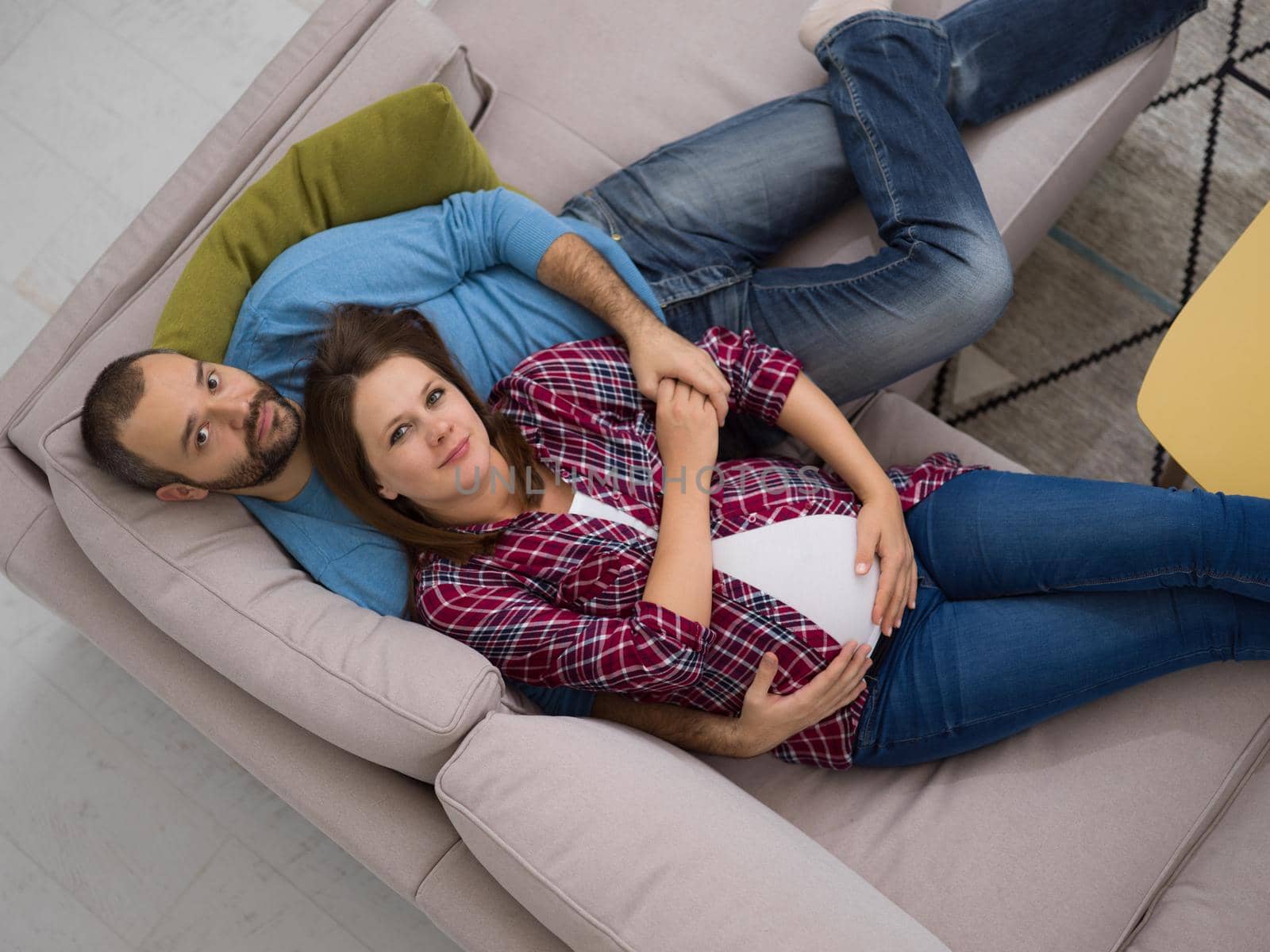 pregnant couple relaxing on sofa by dotshock