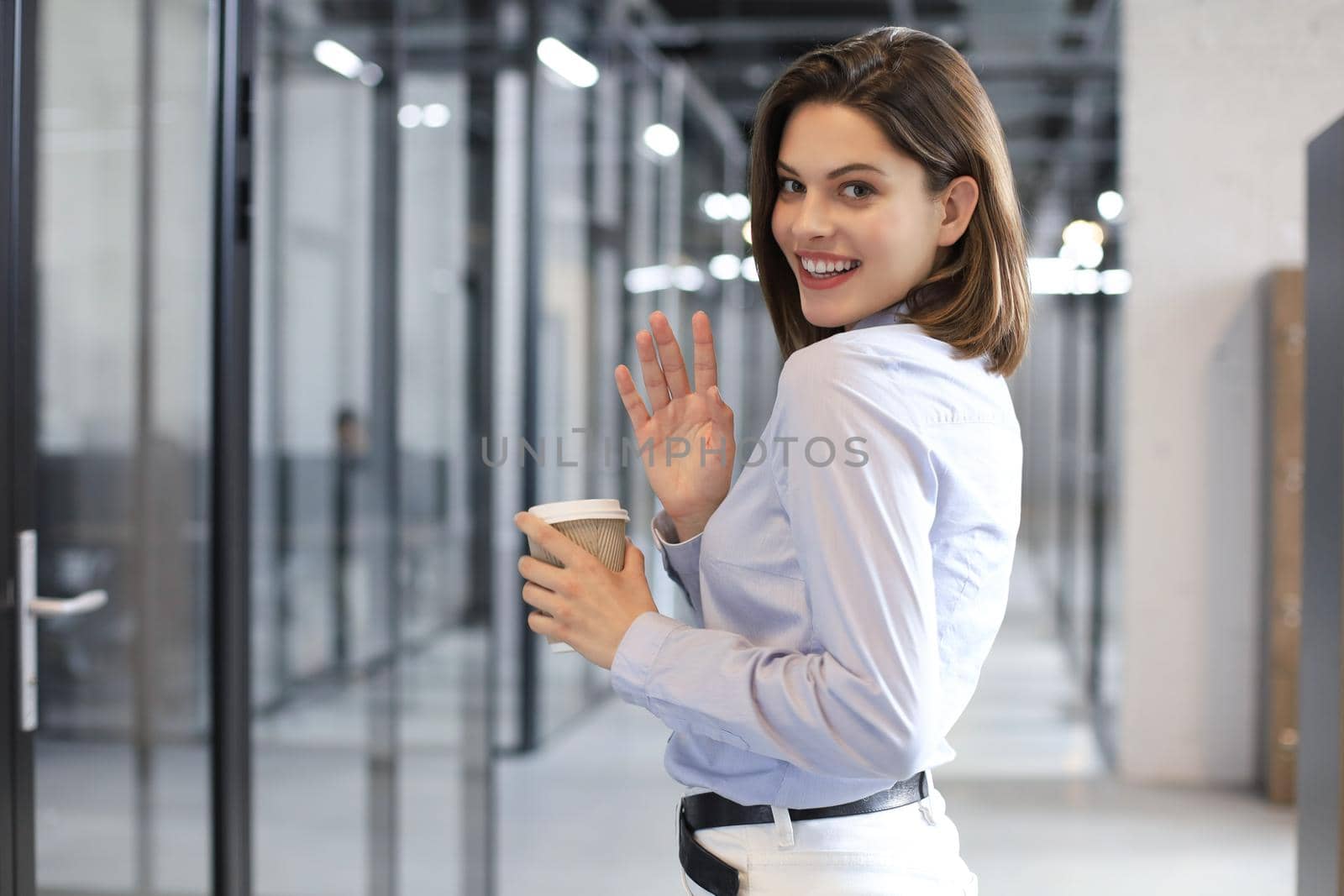 Businesswoman walking along the office corridor with paper