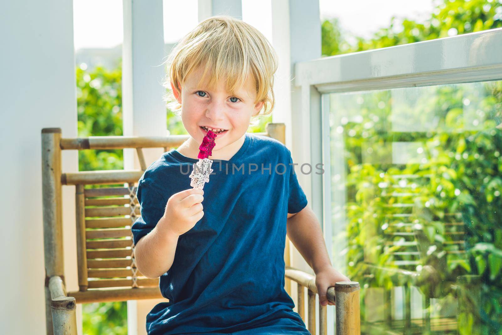 The boy holds smoothies from a dragon fruit with a mint leaf and a drinking straw.