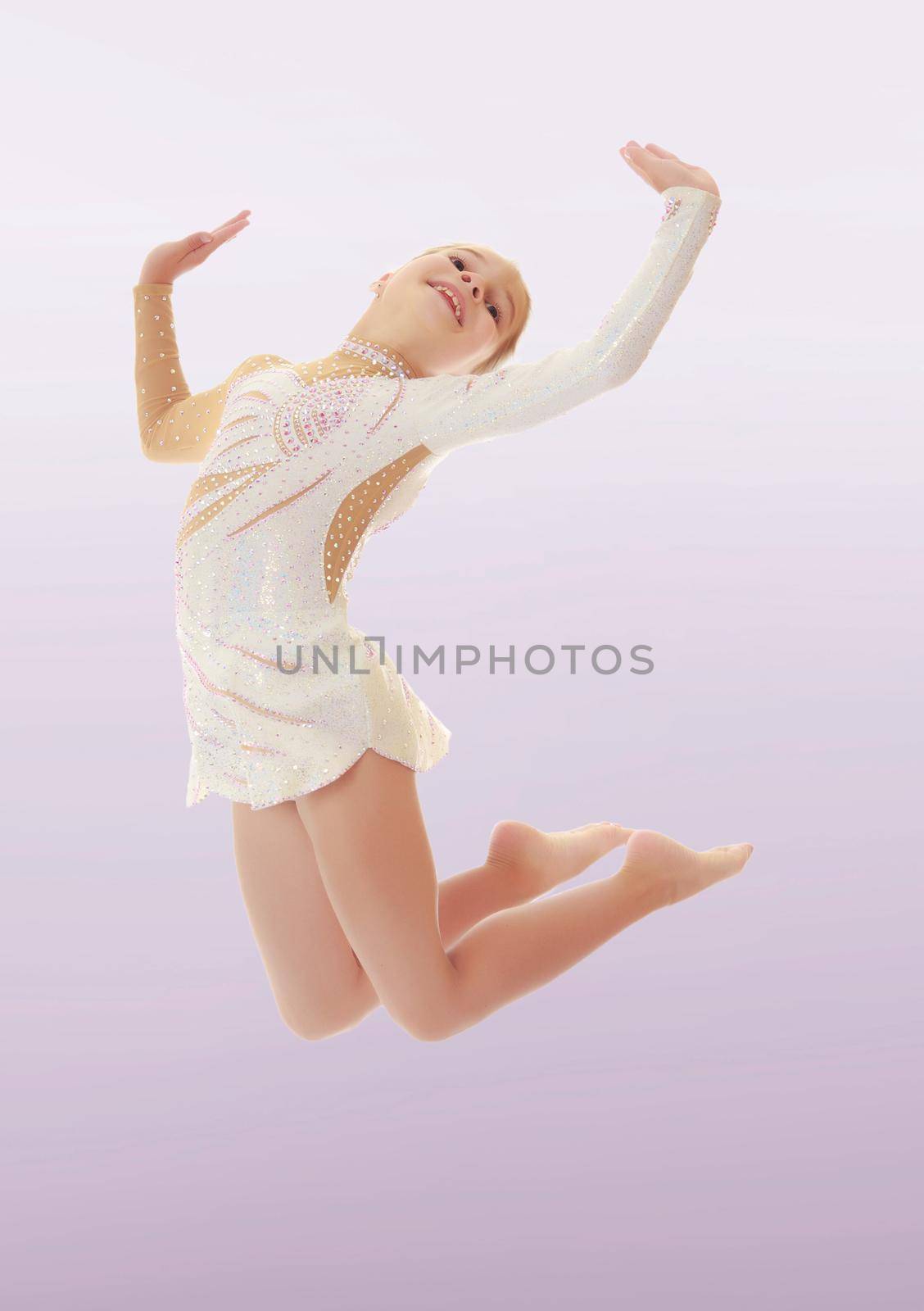 Beautiful little girl gymnast dressed in sports swimsuit, jumps high.On a purple background.