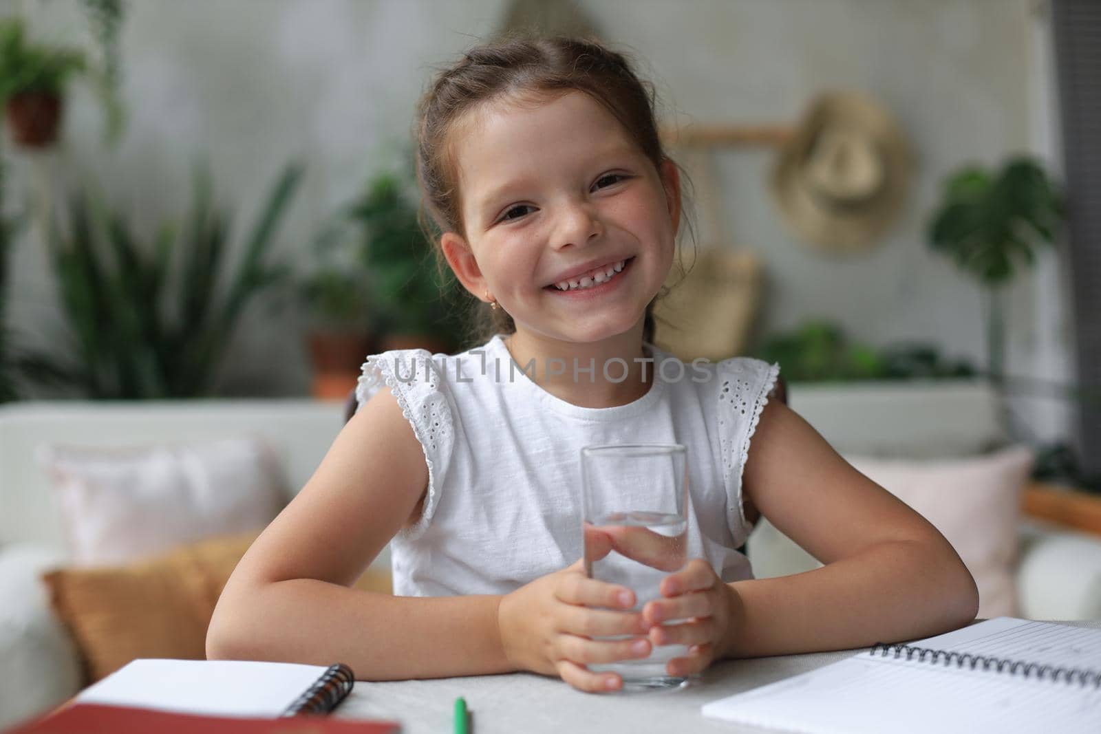 Happy little girl holds crystal still mineral water in glass, small child recommend daily dose of clean aqua.