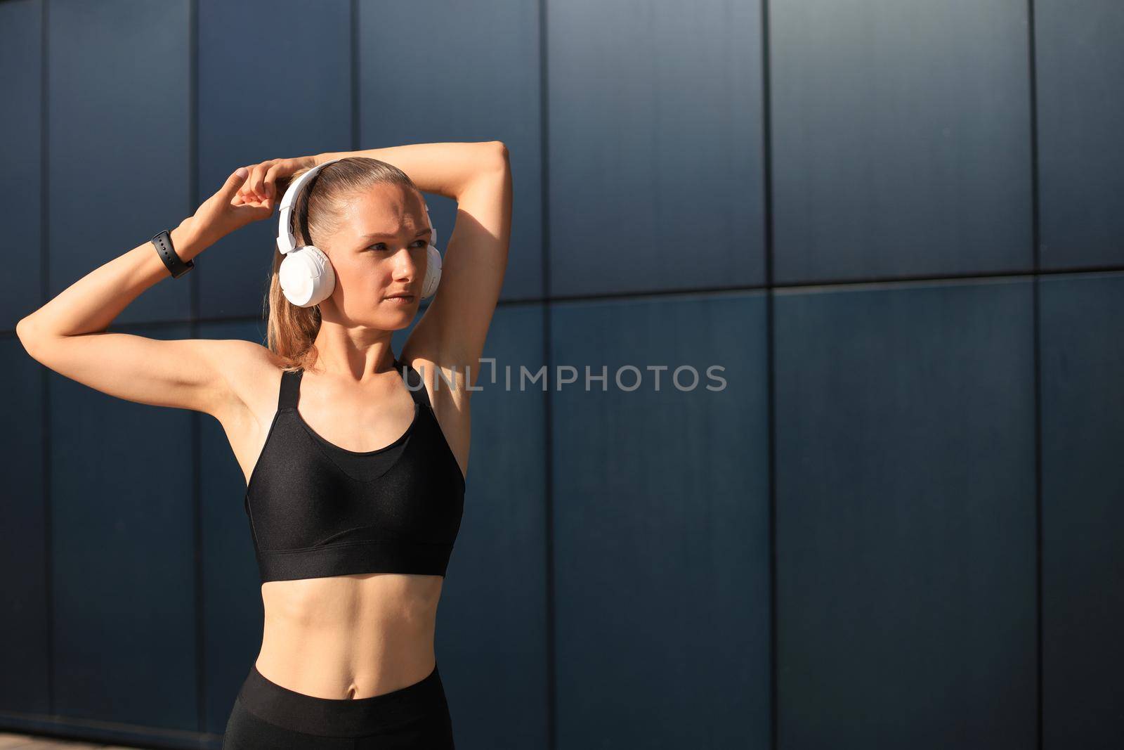 Beautiful woman in sports clothing and earphones looking aside from camera. by tsyhun
