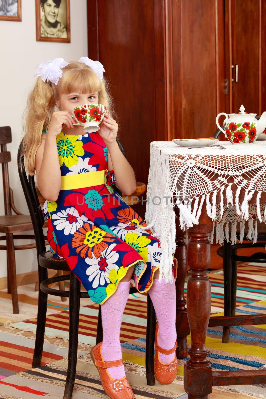 Beautiful little blond girl sitting and drinking a Cup of tea