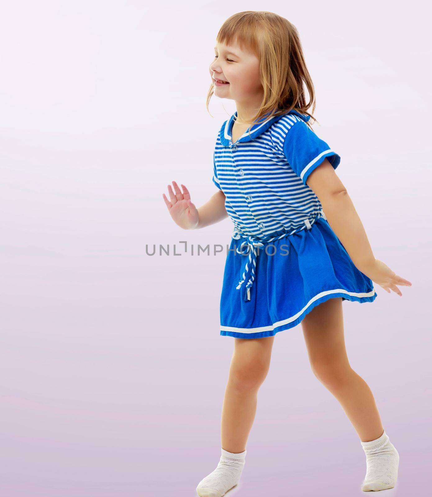 On a purple background, smooth transition from dark to light. Cute little girl in a short blue dress and likes posing for the camera.