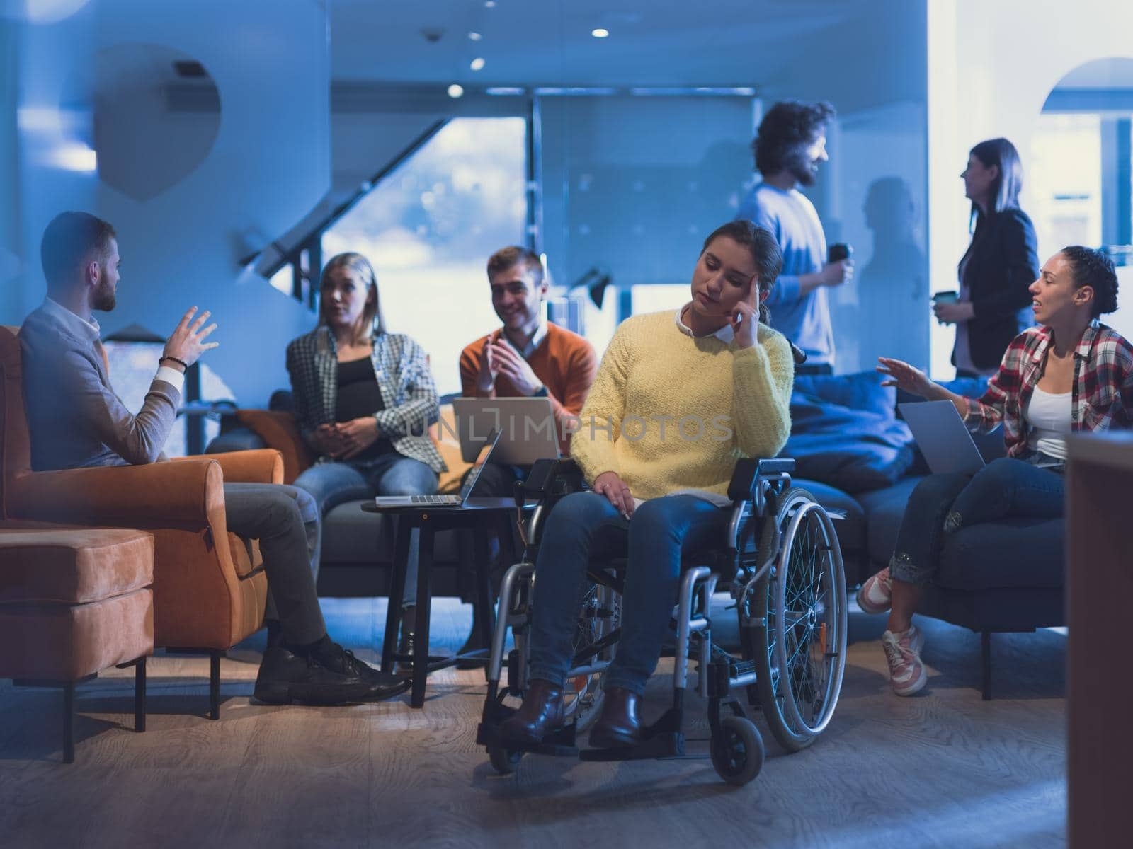 Portrait of disabled businesswoman in a wheelchair in front of her diverse business team in a modern open space coworking office space. High quality photo