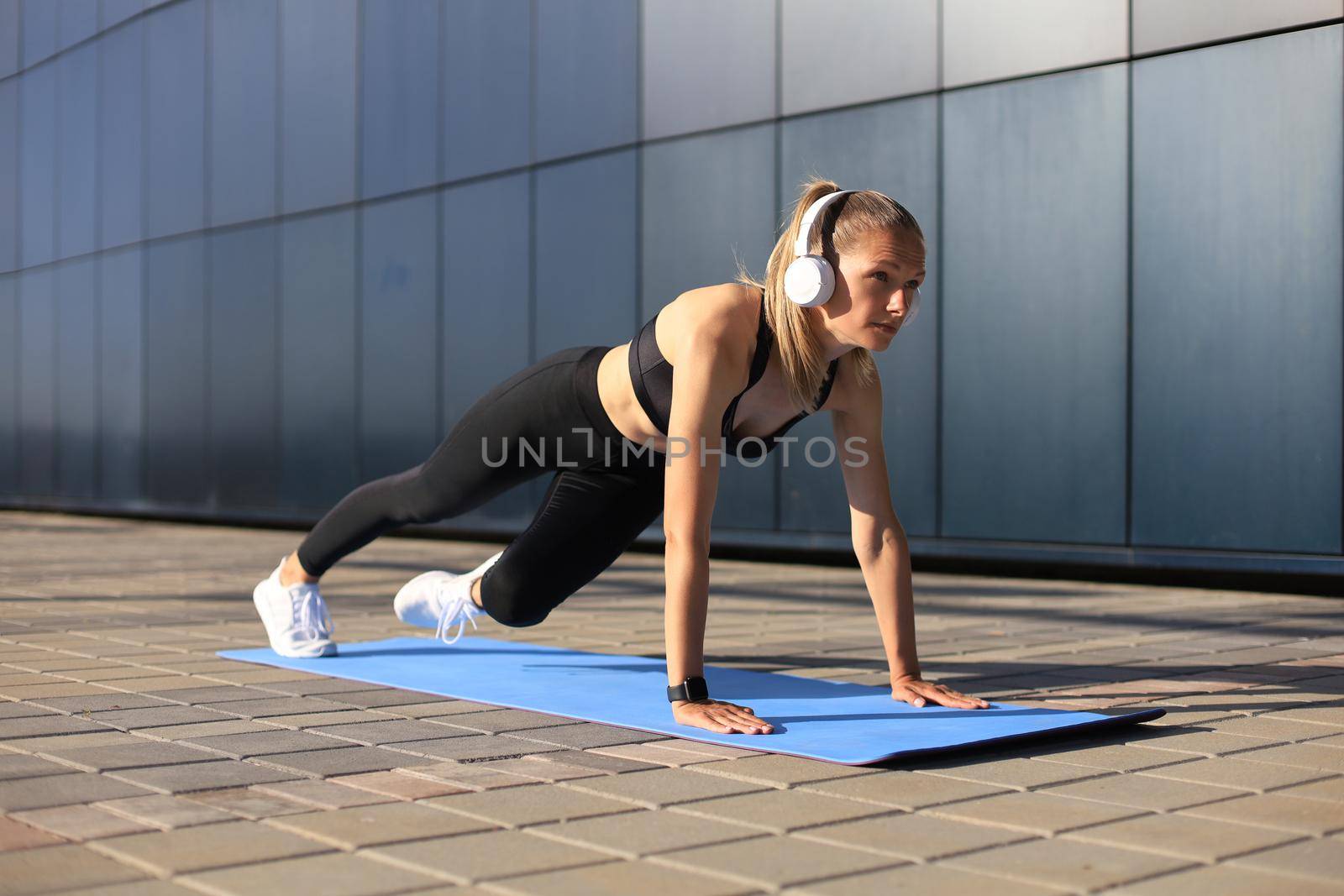 Athletic determined slim woman doing exercises on the blue mat outdoor