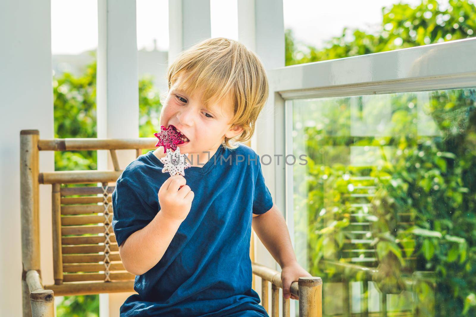 The boy holds smoothies from a dragon fruit with a mint leaf and a drinking straw.