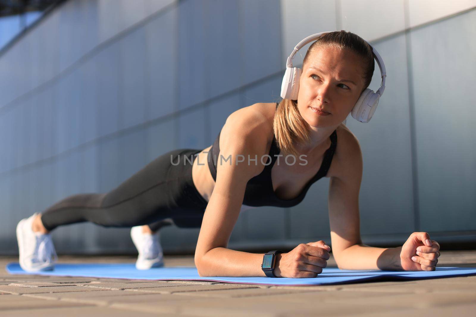 Sport girl doing plank exercise outdoor in warm summer day