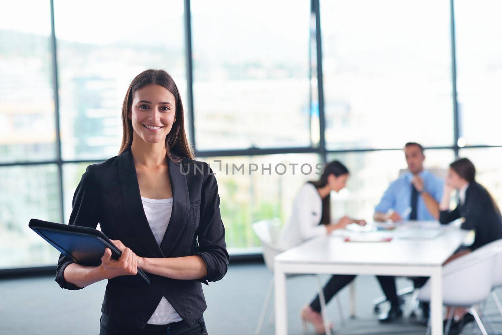 happy young business woman  with her staff,  people group in background at modern bright office indoors