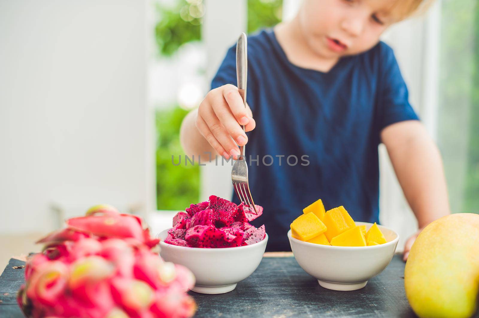 Little cute boy eating mango on the terrace by galitskaya