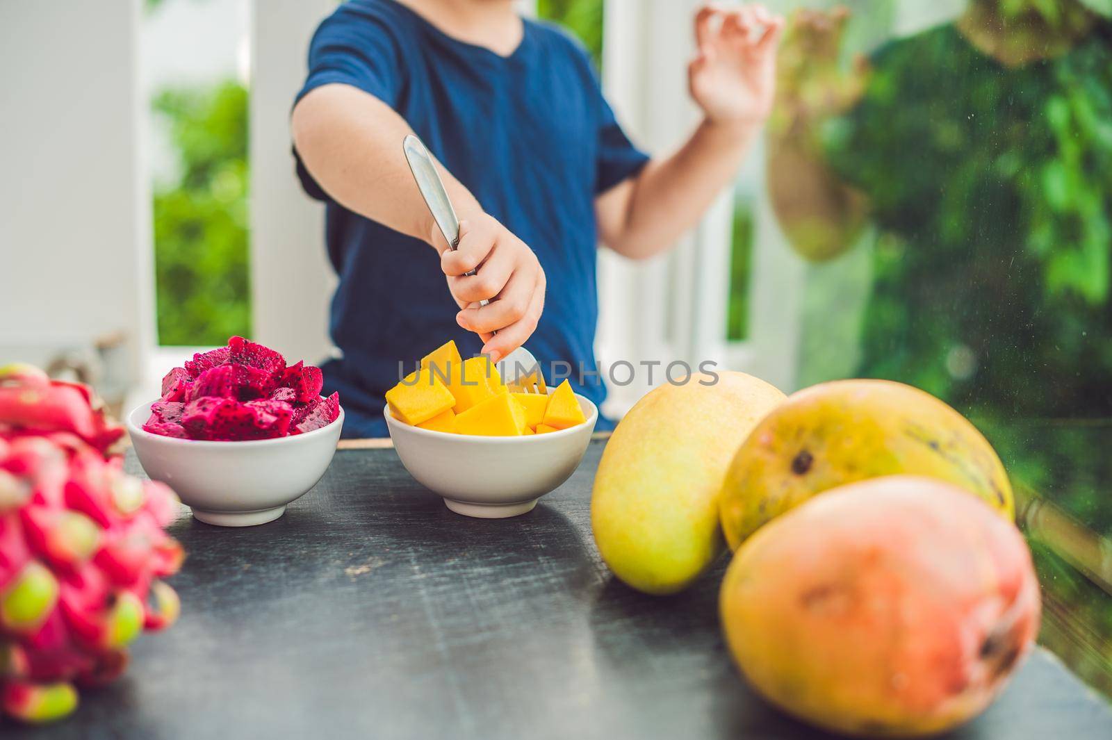 Little cute boy eating mango on the terrace.