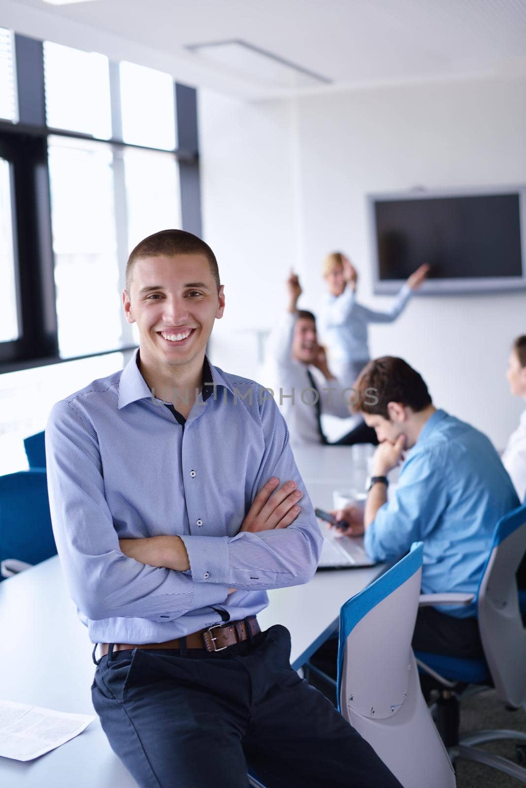 Portrait of a handsome young  business man  on a meeting in offce with colleagues in background