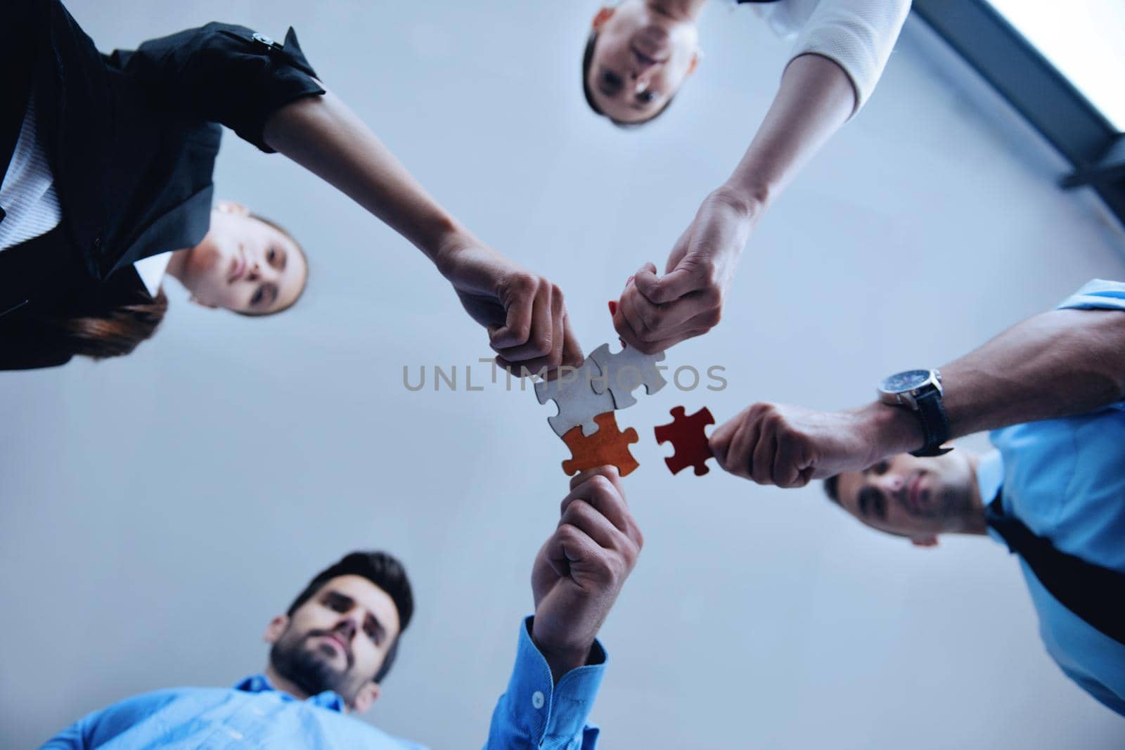 Group of business people assembling jigsaw puzzle by dotshock