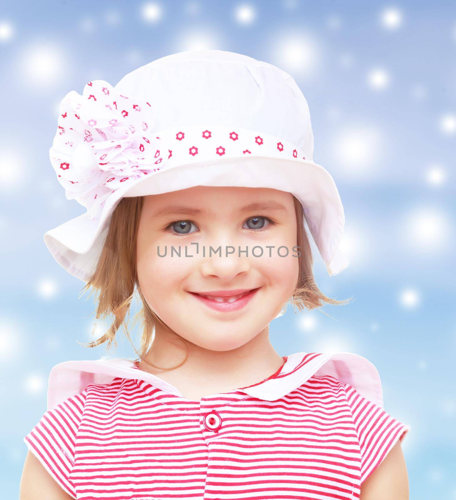 Portrait of beautiful little blond girl in a white hat with a pink bow. Close-up.