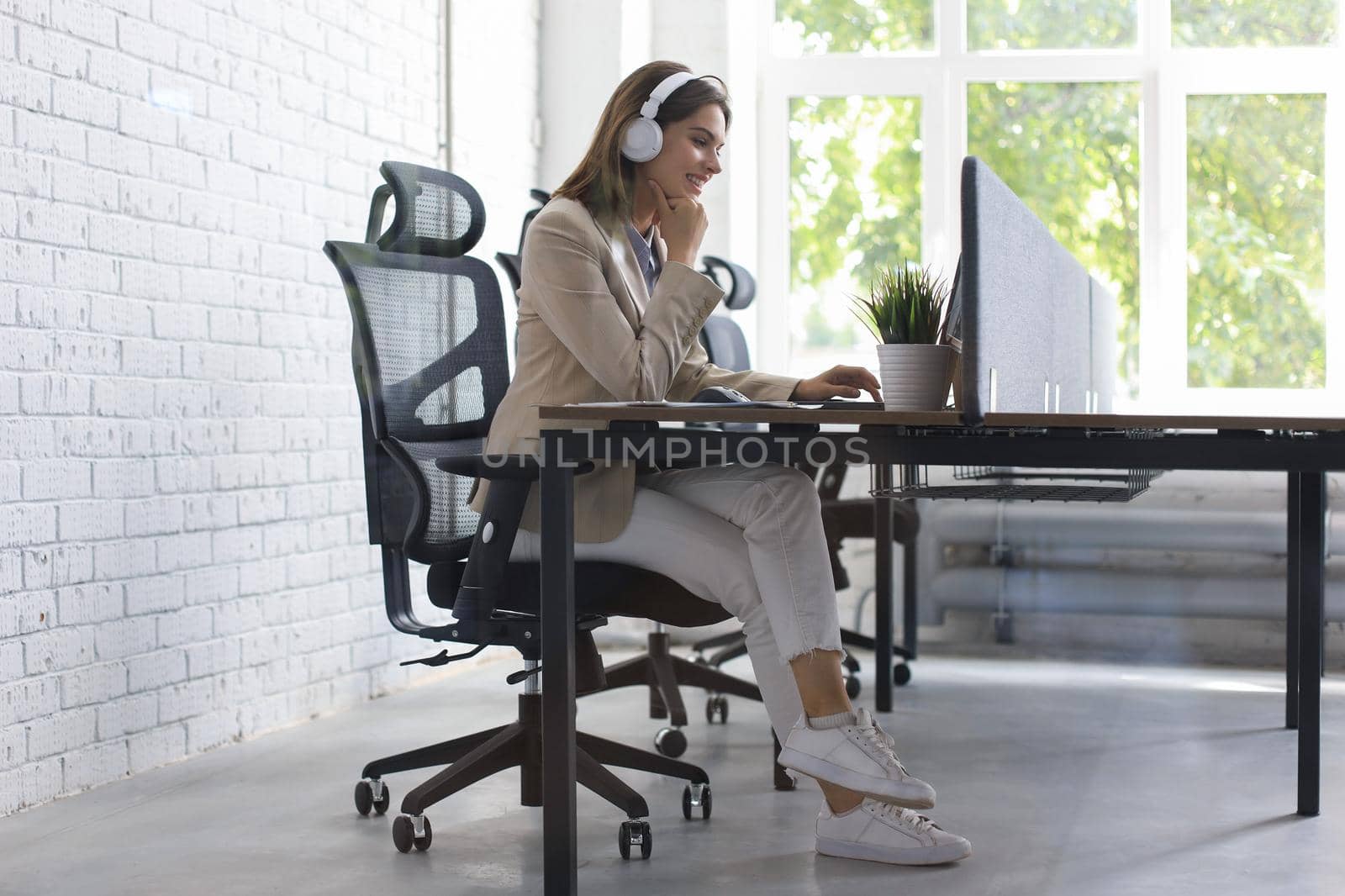 Beautiful caucasian business woman is working using laptop while sitting in creative office. by tsyhun