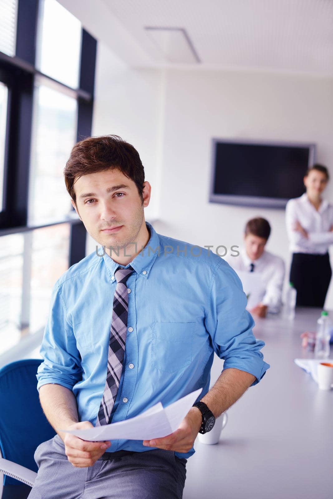 Portrait of a handsome young  business man  on a meeting in offce with colleagues in background