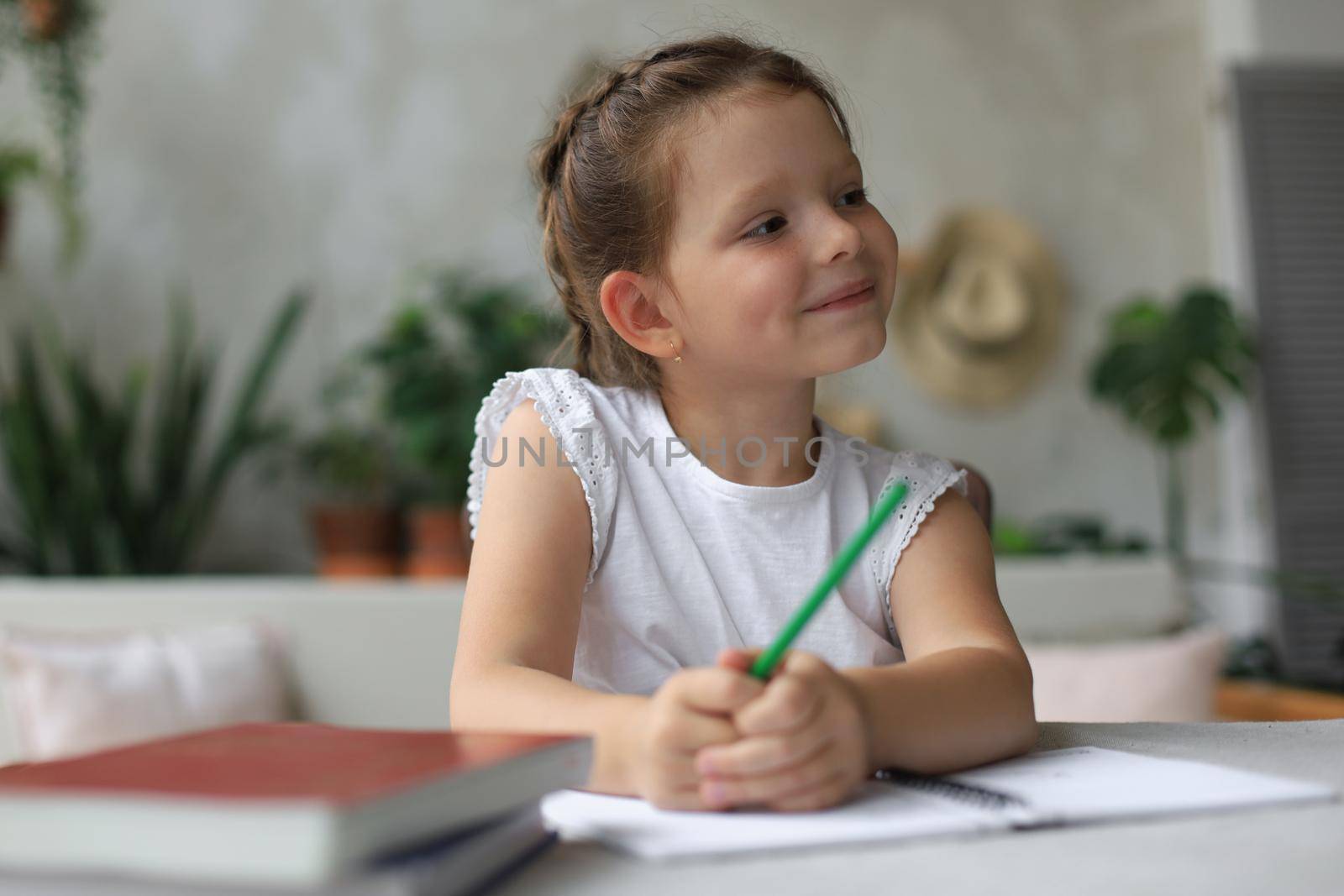 Little girl sit at desk, writing in notebook, do exercises at home, little child handwrite prepare homework. by tsyhun