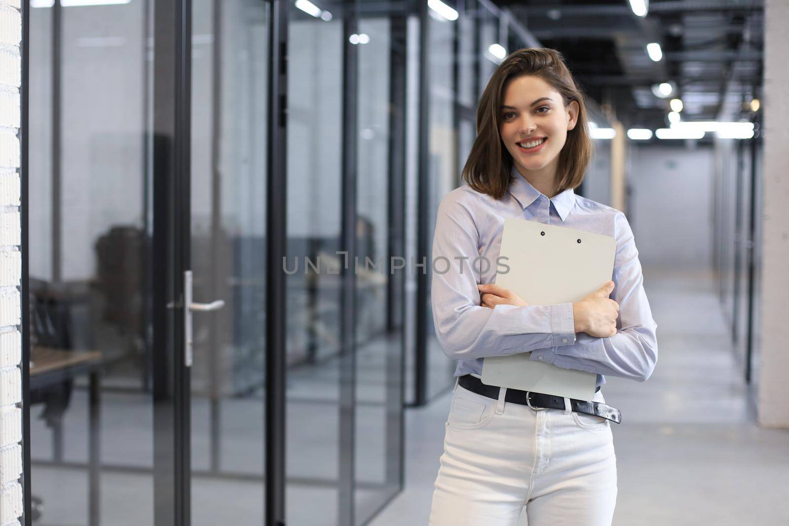 Businesswoman standing in the office corridor with documents