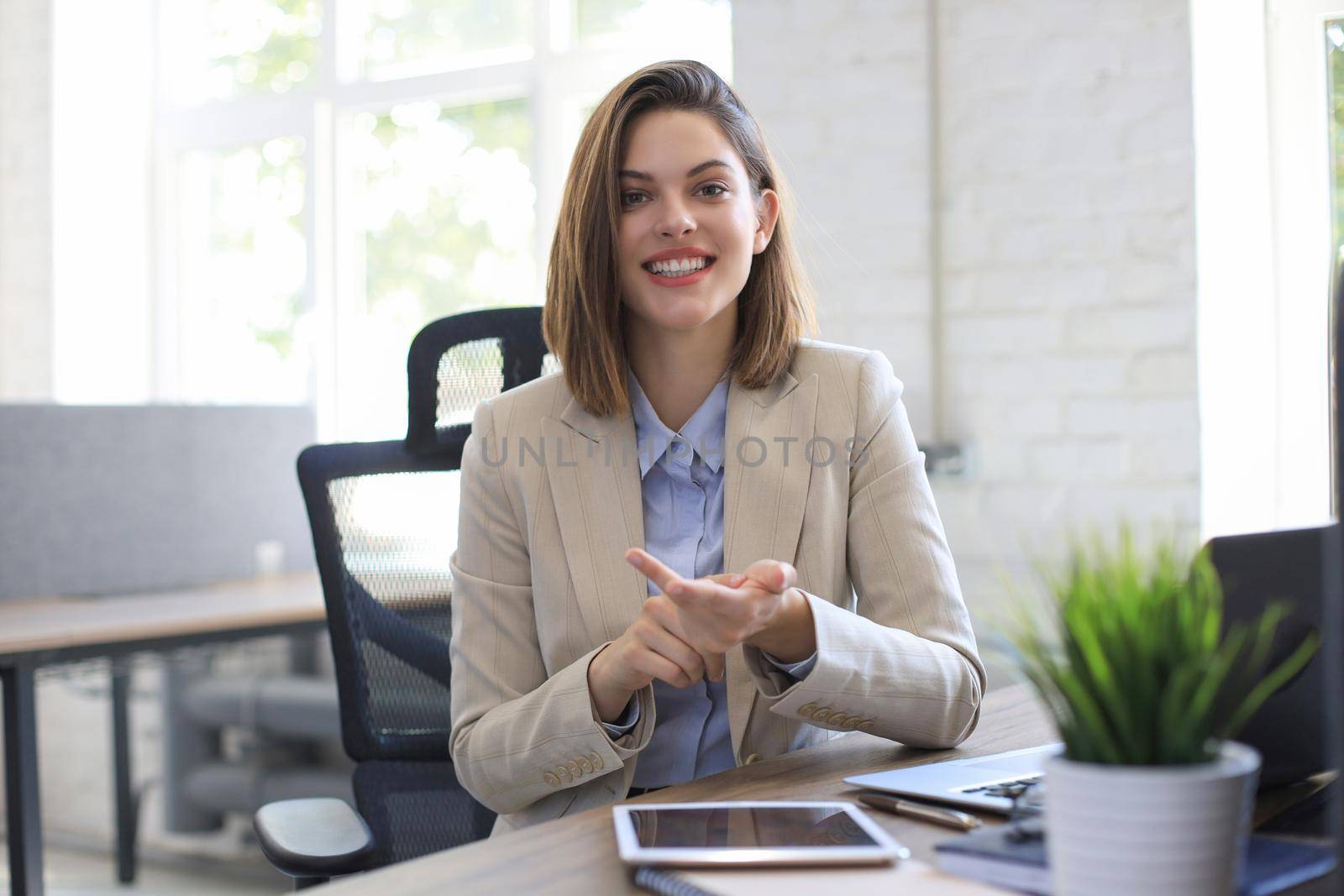 Smiling businesswoman looking at camera, make conference or business call, recording video blog, talking with client