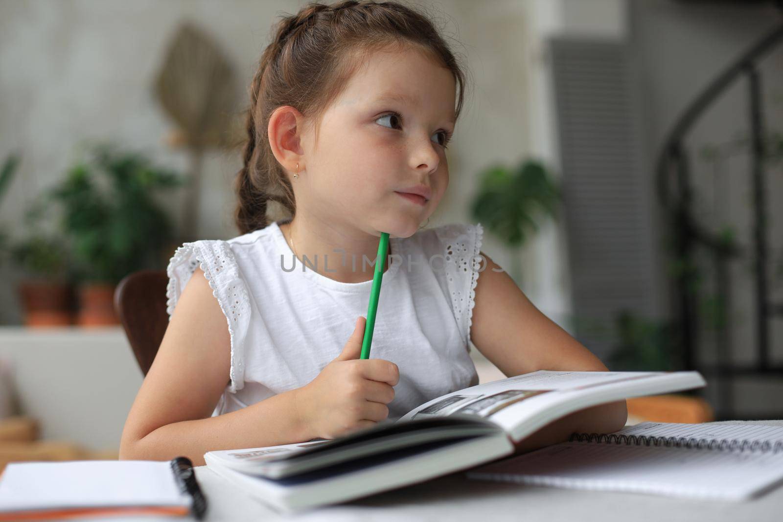 Little girl sits at the desl at home and does homework, self study of the material, reading book. The concept of distance education. by tsyhun