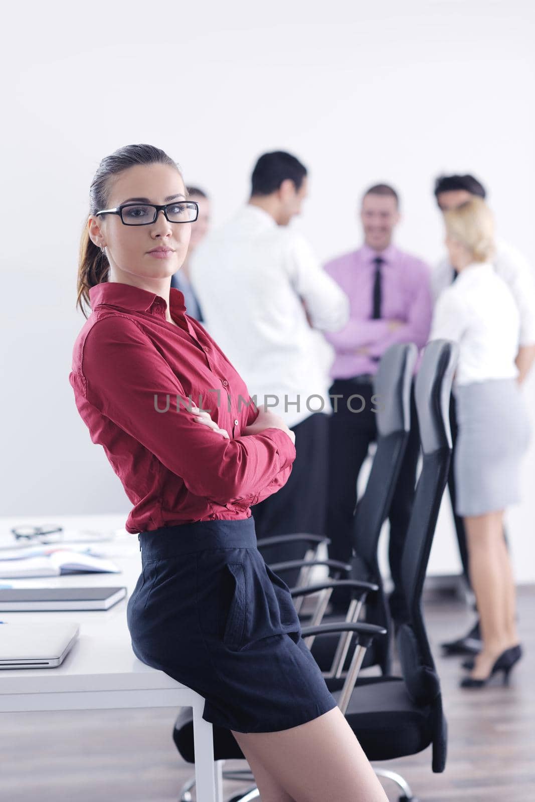 Successful business woman standing with her staff in background at modern bright office