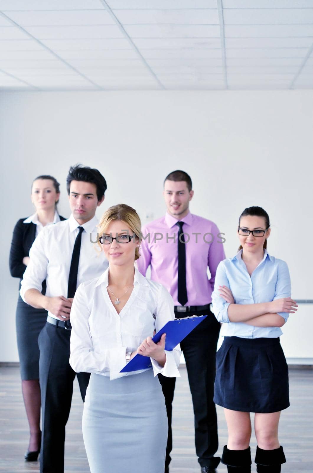 Successful business woman standing with her staff in background at modern bright office