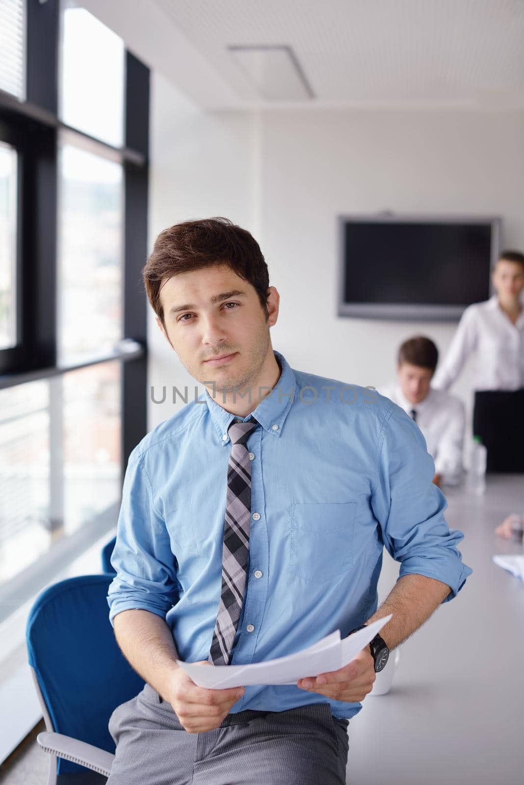 Portrait of a handsome young  business man  on a meeting in offce with colleagues in background