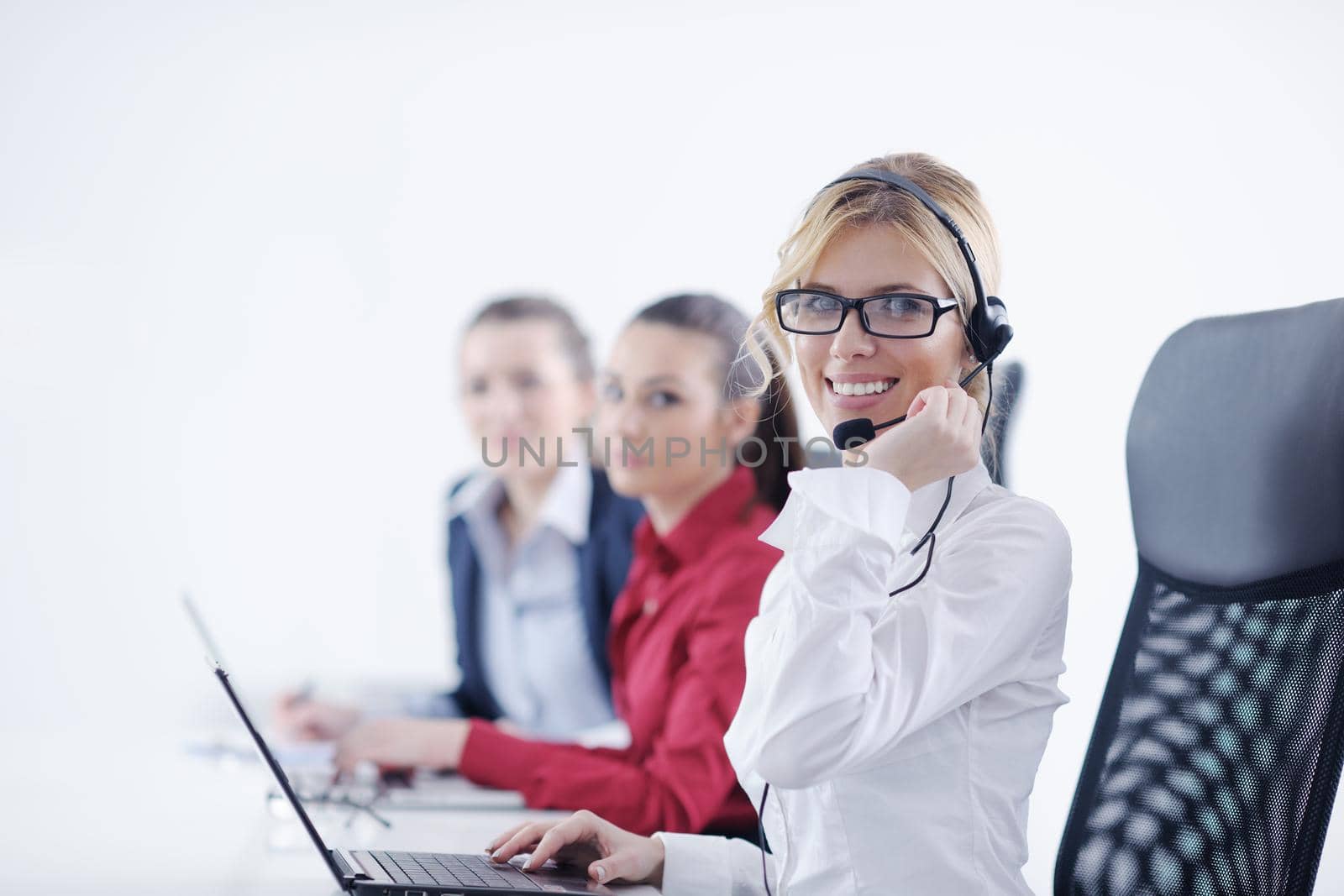 Pretty young business woman group with headphones smiling at you against white background