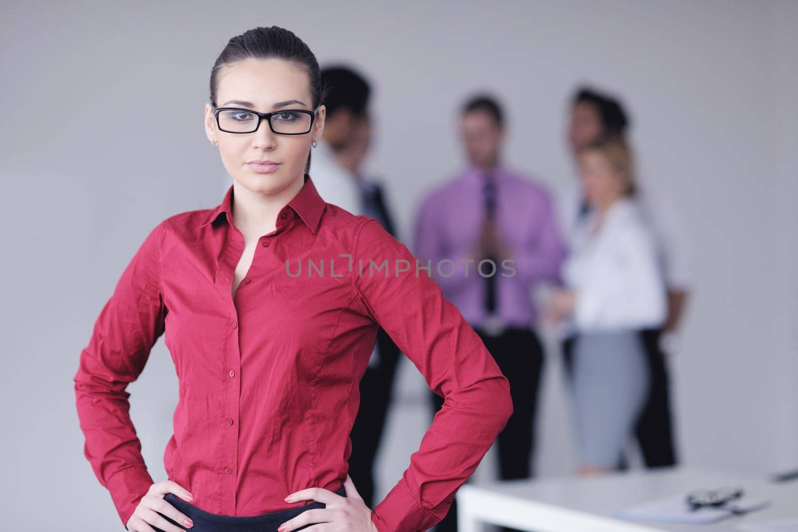 Successful business woman standing with her staff in background at modern bright office