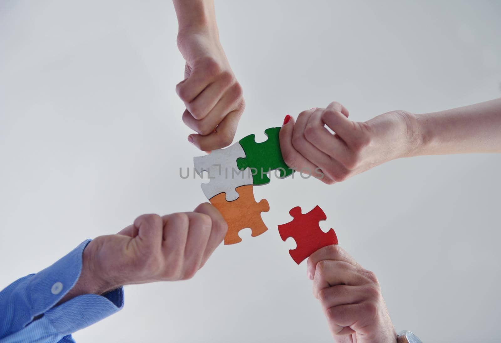 Group of business people assembling jigsaw puzzle by dotshock