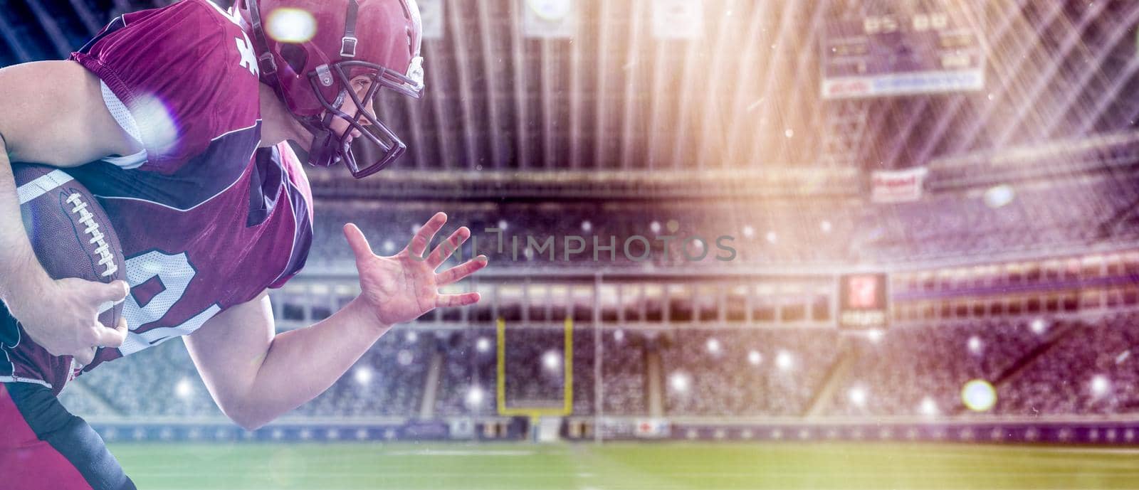 American football Player running with the ball isolated on big modern stadium field with lights and flares