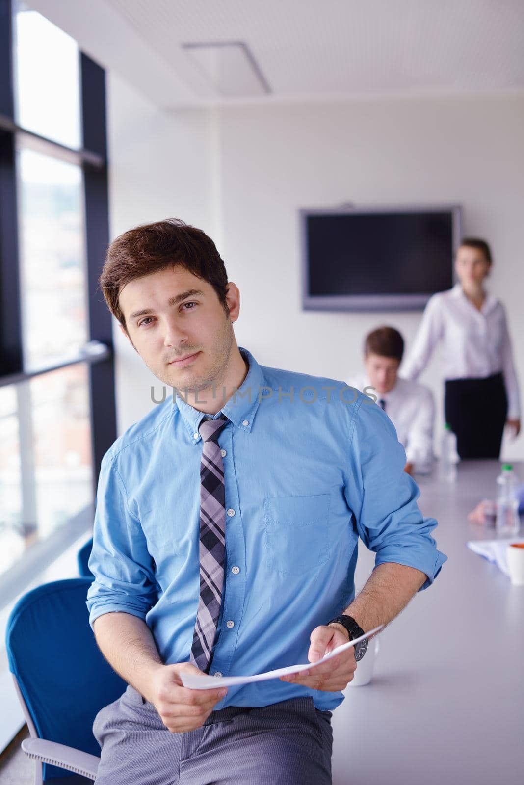Portrait of a handsome young  business man  on a meeting in offce with colleagues in background