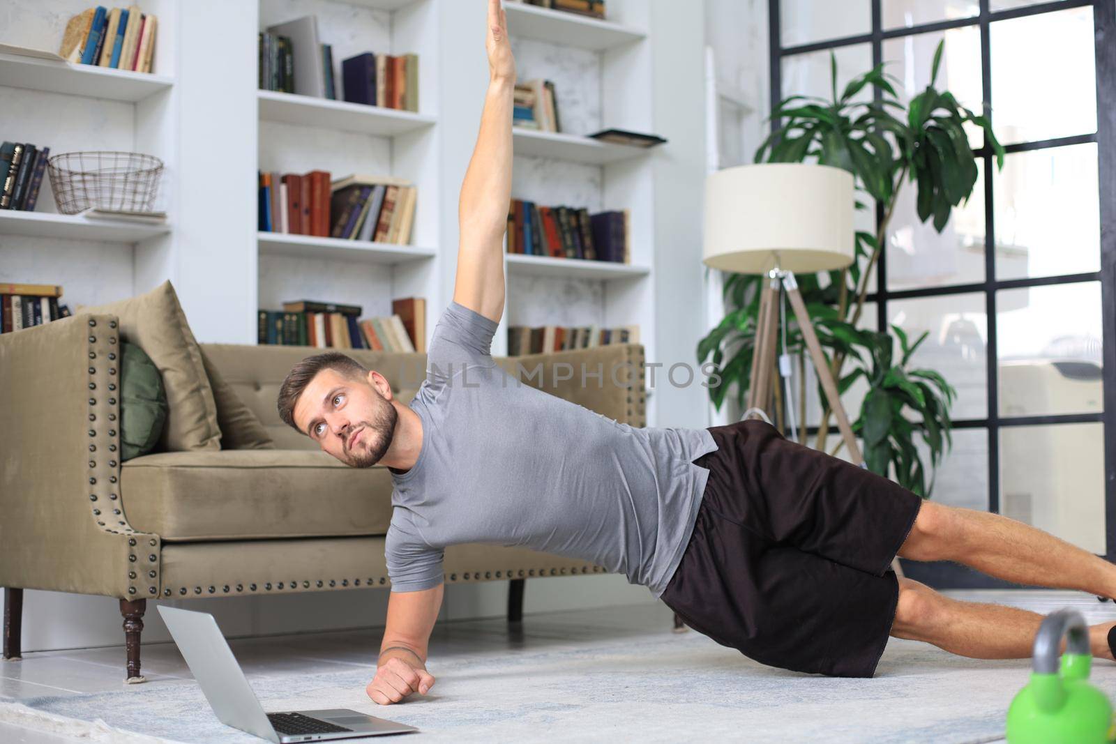 Attractive beared man doing plank exercise at home during quarantine. Fitness is the key to health