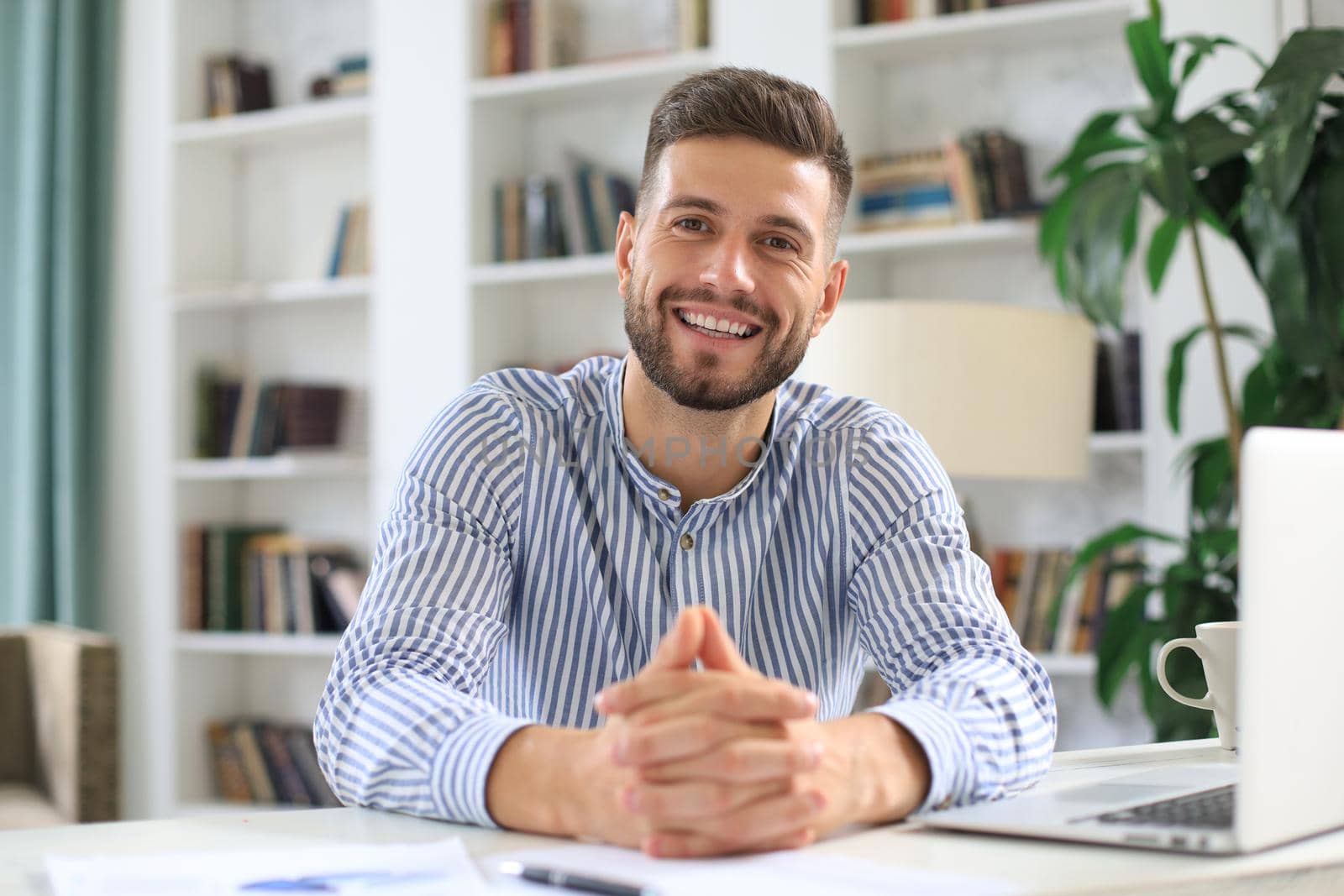 Young modern business man working using laptop while sitting in the office