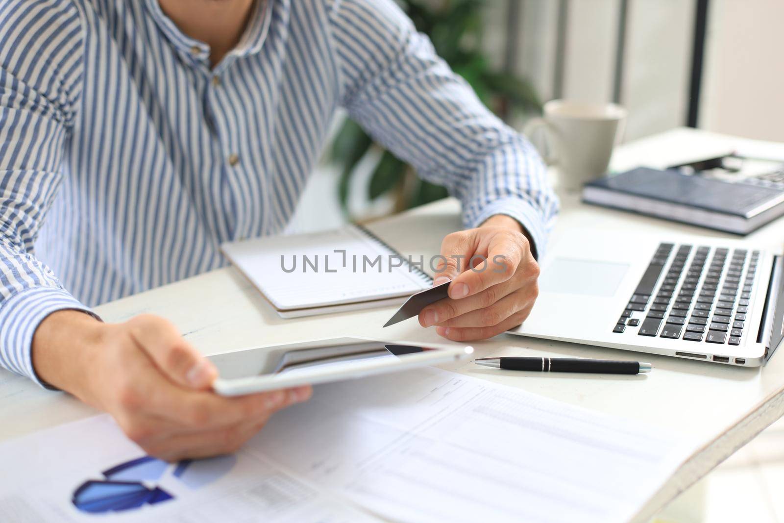 Young modern business man working using digital tablet while sitting in the office. by tsyhun